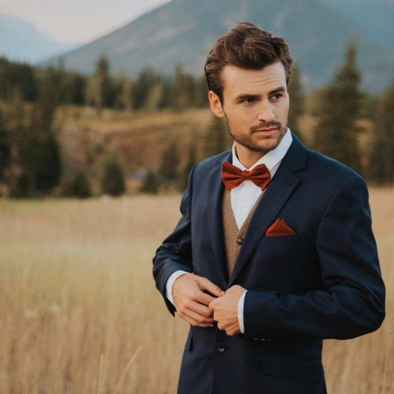 A photo of a man wearing a  burnt orange, cotton mens bow tie and a matching pocket square