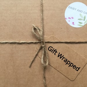 May include: A brown paper package tied with twine and a gift tag that says "Gift Wrapped". A sticker with the text "Daisy and Oak" and a floral design is on the package.
