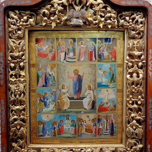 May include: A framed icon with a gold leaf border and a detailed image of Jesus Christ and other biblical figures. The icon is divided into 12 sections, each depicting a different scene from the life of Jesus. The icon is set against a brick wall background.