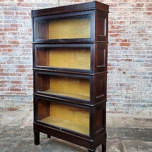 May include: A dark wood bookcase with four glass-fronted shelves. The shelves are empty and have a light wood interior.