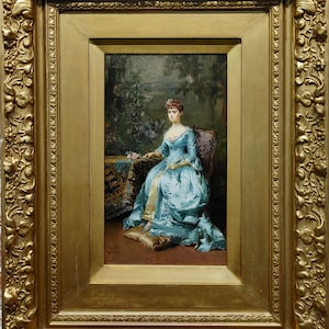 May include: A framed oil painting of a woman in a blue dress sitting in a garden setting. The woman is holding a flower and looking to the side. The painting is signed "E. Dewis, Paris".