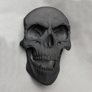 May include: A black skull sculpture with a wide open mouth and sharp teeth. The skull is made of a smooth, matte material and has a realistic appearance.