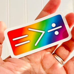 May include: A rainbow sticker with the text "= > :" in white.