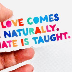 Puede incluir: Una pegatina colorida con el texto "El amor viene naturalmente. El odio se enseña."