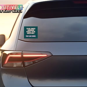K&ouml;nnte beinhalten: Ein dunkel t&uuml;rkisfarbener Aufkleber auf einer Autoscheibe mit dem Text "I'M NO LONGER SHRINKING MYSELF TO BE DIGESTIBLE. YOU CAN CHOKE." Der Aufkleber ist rechteckig und das Auto ist dunkelgrau.