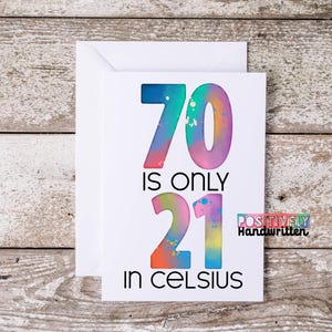 May include: A white greeting card with the text "70 is only 21 in Celsius" in colorful, watercolor-style lettering. The card is inside a white envelope, set against a rustic wooden background. The words "Positively Handwritten" are also on the card.