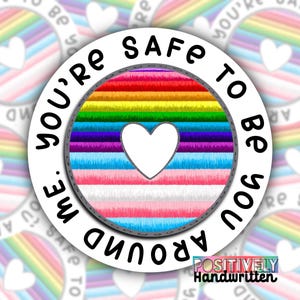 Könnte beinhalten: Ein weißer runder Aufkleber mit dem Text "You're safe to be you around me." in Schwarz. Der Aufkleber hat im Zentrum ein Regenbogen- und Transgender-Pride-Flaggen-Design mit einem weißen Herzen.
