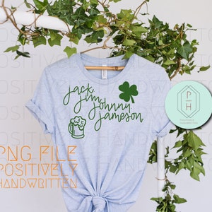Può includere: Una maglietta blu chiaro con un trifoglio verde e il testo "Jack Jim Johnny Jameson" e una grafica di una boccale di birra verde.