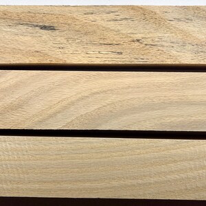 Puede incluir: Tres piezas de madera de pino roble sin terminar, cada una mide 5,1 x 5,1 x 30,5 cm. La madera es de color marr&oacute;n claro y tiene un patr&oacute;n de veta natural. Las piezas est&aacute;n etiquetadas con los n&uacute;meros 105, 106 y 107.