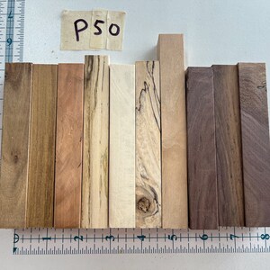 May include: A collection of ten wooden dowels in various shades of brown, beige, and white. The dowels are arranged in a row and labeled "P50".