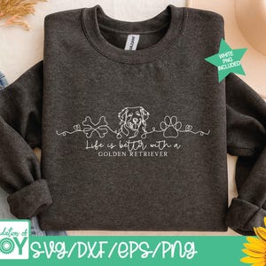 Op de afbeelding: Donkergrijze sweatshirt met de witte tekst "Life is better with a Golden Retriever". Het ontwerp bevat een bot, een hondenhoofd en een pootafdruk. De woorden "WHITE PNG INCLUDED" zijn ook zichtbaar.