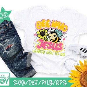 May include: A white t-shirt featuring a cartoon bee and the text "Bee Who Jesus Wants You To Be!" in colourful bubble letters. The bee has a yellow and black striped body with a cute face and wings. The design is surrounded by small hearts and stars.