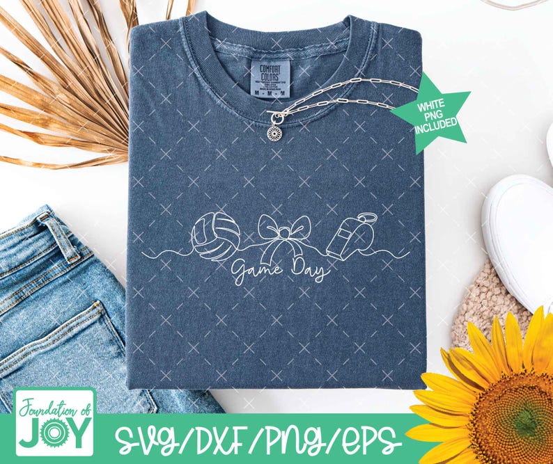 May include: A blue t-shirt with a white graphic of a volleyball, bow, and whistle, with the words "Game Day". The shirt has a crew neck and short sleeves. A silver necklace is draped on the shirt. The text "WHITE PNG INCLUDED" is on a green star.