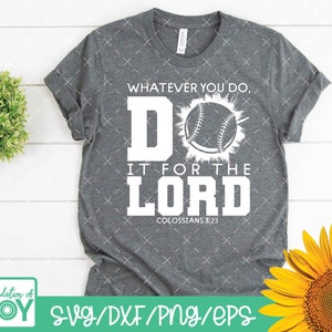 May include: A gray t-shirt with the text "WHATEVER YOU DO, DO IT FOR THE LORD COLOSSIANS 3:23" in white. A baseball graphic is centered above the text. The shirt has rolled-up sleeves and is displayed with a sunflower and greenery.