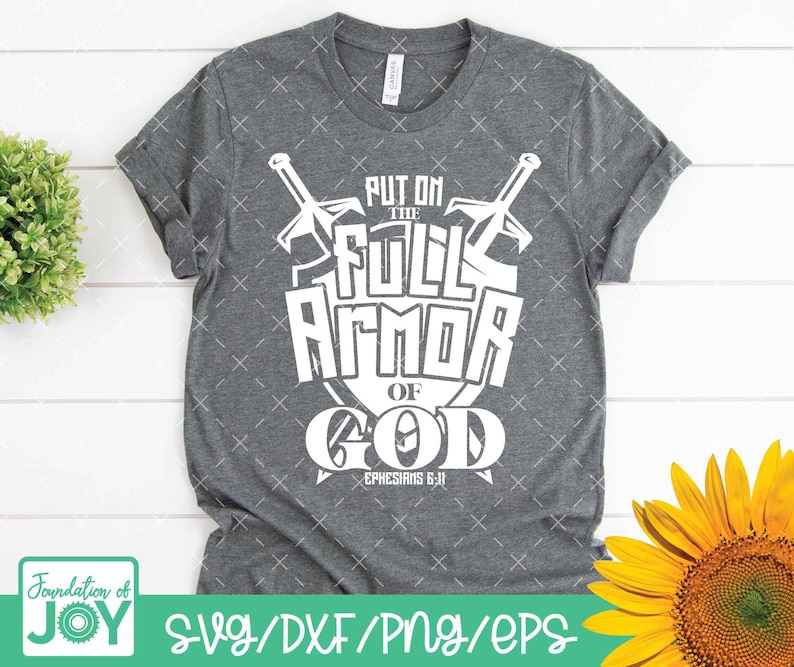 May include: A gray t-shirt with a white graphic design that says "Put on the Full Armor of God Ephesians 6:11". The graphic features two swords crossed over a shield.