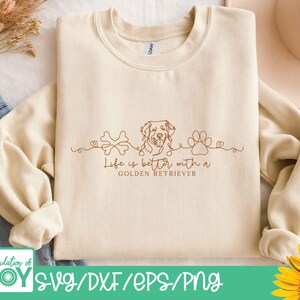 Op de afbeelding: Cr&egrave;mekleurige sweatshirt met een bruine lijntekening van een Golden Retriever, een bot en een pootafdruk. De tekst "Life is better with a Golden Retriever" staat onder de tekening. De onderkant van de afbeelding heeft de tekst "SVG/DXF/EPS/PNG".