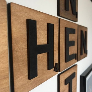 May include: Wooden tiles with black letters spelling out the word "THEN". The tiles are arranged in a square shape and have a natural wood grain.