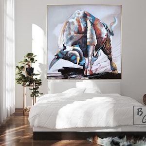 Puede incluir: Una pintura abstracta colorida de un toro cargando hacia adelante. El toro est&aacute; pintado en tonos de azul, rojo, blanco y marr&oacute;n. El fondo es gris claro con toques de rosa y morado.