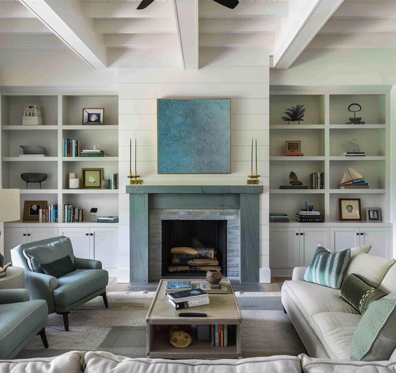 May include: A living room with a fireplace, built-in bookshelves, and a light-colored sofa and chairs. The fireplace is painted a muted blue-green, and a blue abstract painting hangs above it. The room has a neutral color palette.