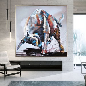 Puede incluir: Una gran pintura abstracta de un toro cargando con un esquema de color blanco, azul y naranja. El toro est&aacute; pintado en un estilo estilizado, casi cubista, con &aacute;ngulos agudos y l&iacute;neas audaces. La pintura est&aacute; sobre un fondo gris claro.