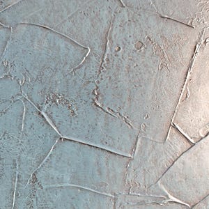 May include: Abstract textured artwork with a palette of muted blue and gray tones. The surface is composed of overlapping, irregular shapes, creating a layered effect. The texture appears rough and uneven, with visible brushstrokes and a subtle sheen.