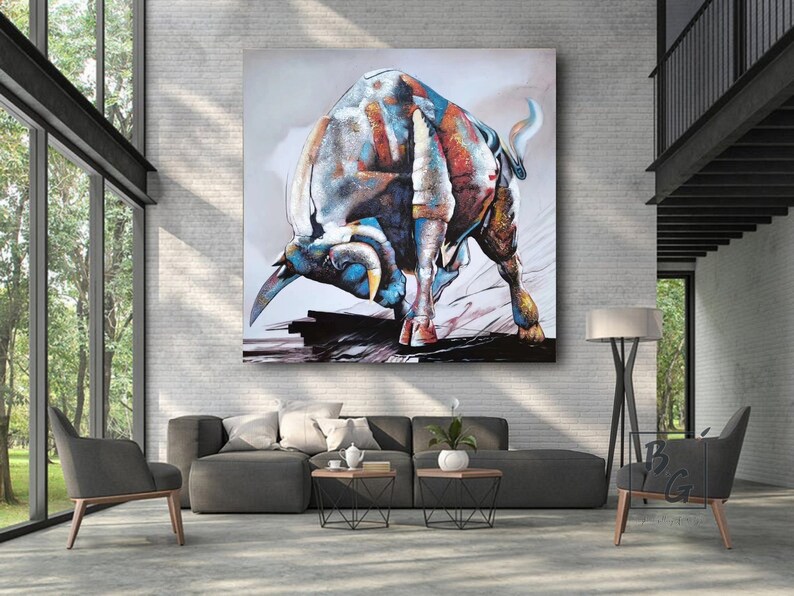 Puede incluir: Pintura abstracta de un toro cargando en tonos de azul, rojo y dorado. El toro est&aacute; representado en una pose din&aacute;mica con la cabeza baja y los cuernos apuntando hacia adelante. El fondo es de un gris apagado con toques de blanco y marr&oacute;n.