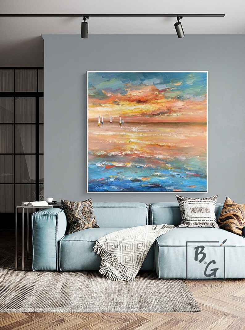 Puede incluir: Una gran pintura abstracta de un paisaje mar&iacute;timo con un cielo de puesta de sol en tonos naranja, amarillo y azul. La pintura presenta algunos peque&ntilde;os veleros blancos en la distancia.