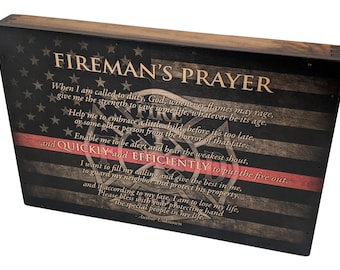 Puede incluir: Un letrero de madera con un diseño de bandera estadounidense en blanco y negro y una franja roja en la parte inferior. El letrero presenta el texto "Fireman's Prayer" y un poema sobre los deberes de un bombero.