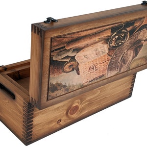 May include: A wooden box with a hinged lid. The lid features a printed image of fishing gear, including a fishing rod, a fishing reel, a hat, and a wicker basket. The box is stained a dark brown color.