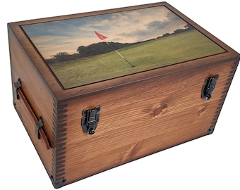 May include: A wooden box with a hinged lid and metal clasps. The lid features a printed image of a golf course with a red flag.