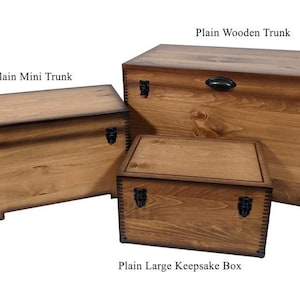 May include: Three wooden storage boxes with hinged lids and metal clasps. The smallest box is labeled "Plain Mini Trunk", the middle box is labeled "Plain Wooden Trunk", and the largest box is labeled "Plain Large Keepsake Box".