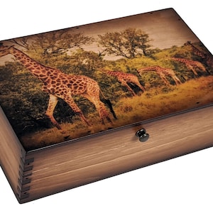 May include: A wooden box with a hinged lid and a brass knob. The lid features a printed image of a group of giraffes walking through a savanna landscape.