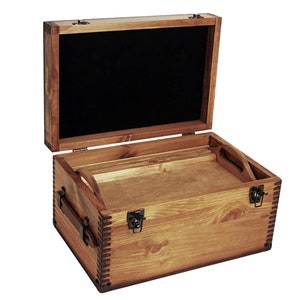 May include: A wooden storage box with a hinged lid and brass clasps. The box is made of natural wood with a dark brown stain. The inside of the box is lined with black fabric.