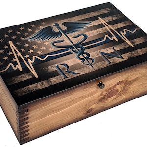 May include: Wooden box with a distressed American flag design, a blue medical caduceus symbol, a blue and white heartbeat line, and the text "RN".