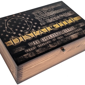 May include: Wooden box with a black and gold American flag design. The text on the box reads "Between the Thin Red Line & The Thin Blue Line Lies the Thinnest Gold Line Those Who Are Rarely Seen But Mostly Heard. The Calm Voices in the Dark Night DISPATCHER THE GOLDEN GLUE THAT HOLDS IT ALL TOGETHER"
