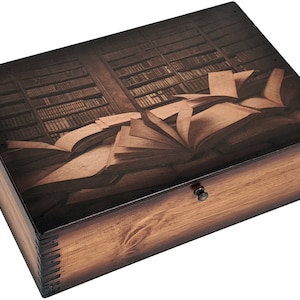 May include: A wooden box with a hinged lid and a brass latch. The lid features a printed image of a library bookshelf with open books on a table.