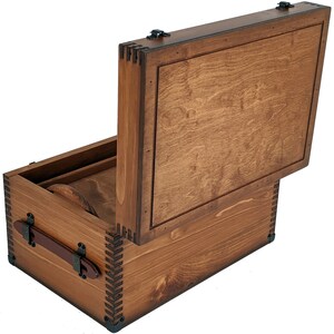 May include: A wooden box with a hinged lid, the lid is open and the box is made of brown wood with a natural finish. The box has a leather handle and metal accents.