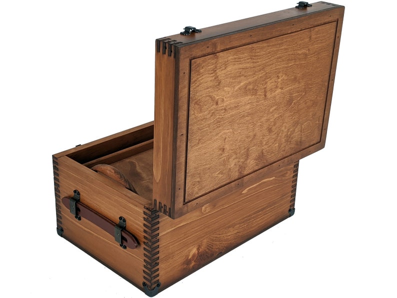 May include: A wooden box with a hinged lid, the lid is open and the box is made of brown wood with a natural finish. The box has a leather handle and metal accents.