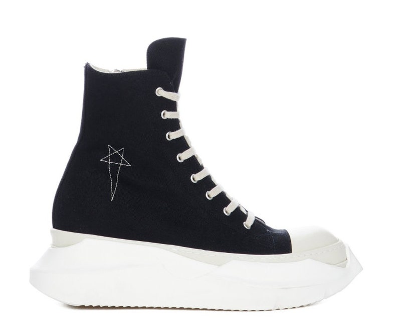 K&ouml;nnte beinhalten: Schwarze High-Top-Canvas-Sneaker mit wei&szlig;er Plateau-Sohle und einem Stern-Design an der Seite.