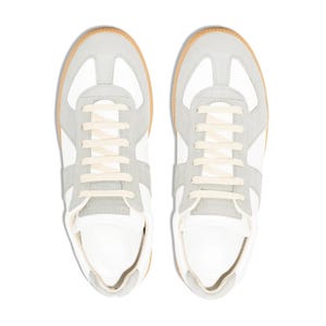 May include: A pair of white and gray sneakers with cream-colored laces. The shoes have a light brown sole and a classic design. The sneakers are viewed from above, showcasing their symmetrical appearance and clean lines.
