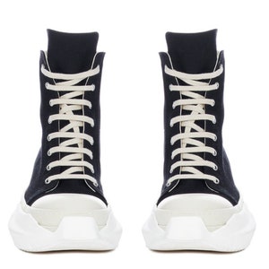 K&ouml;nnte beinhalten: Schwarze High-Top-Sneaker mit wei&szlig;en Schn&uuml;rsenkeln und einer dicken wei&szlig;en Plateau-Sohle.