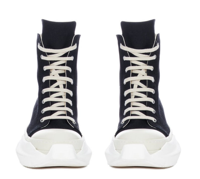 K&ouml;nnte beinhalten: Schwarze High-Top-Sneaker mit wei&szlig;en Schn&uuml;rsenkeln und einer dicken wei&szlig;en Plateau-Sohle.