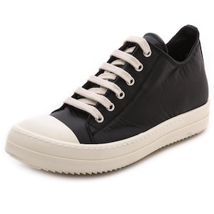 K&ouml;nnte beinhalten: Schwarze Low-Top-Sneaker mit wei&szlig;en Schn&uuml;rsenkeln und einer wei&szlig;en Gummisohle.