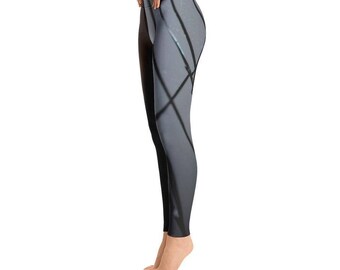 May include: Full-length leggings featuring a split design with a solid black panel on the inner leg and a light gray panel on the outer leg, accented by a dark, intersecting geometric line pattern that creates a sharp, angular visual effect.