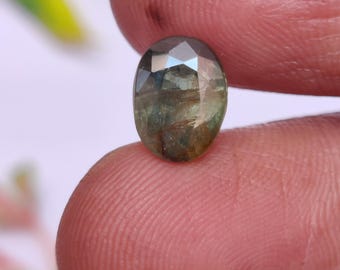 May include: A green and blue oval-shaped gemstone with a faceted cut.