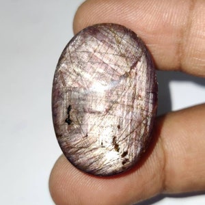 May include: A large, oval-shaped, purple and silver gemstone with a shimmery, iridescent finish. The gemstone has a unique, striated pattern and is set in a cabochon cut.