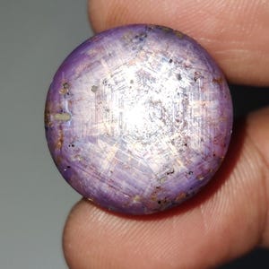 以下が含まれることがあります： 星形の模様が入った丸い紫色の宝石。宝石は銀色の光沢があり、カボションカットされています。