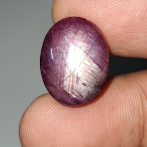 May include: An oval-shaped gemstone with a star-like pattern inside, in a shade of pink.