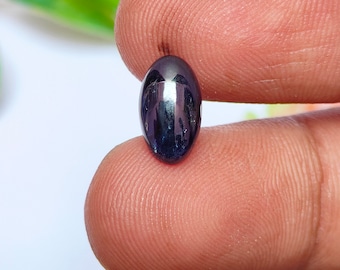 Pode incluir: Uma gema oval de cor azul escura com uma superfície brilhante e reflexiva.