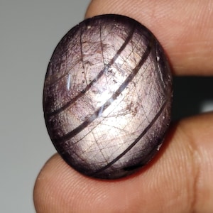 May include: A round, purple gemstone with silver streaks and a smooth, polished surface.